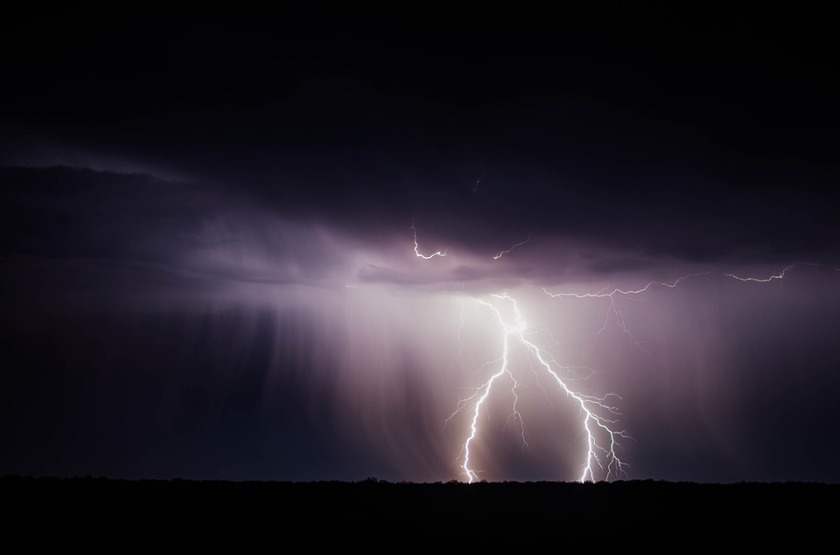 lightning striking the ground under dark clouds