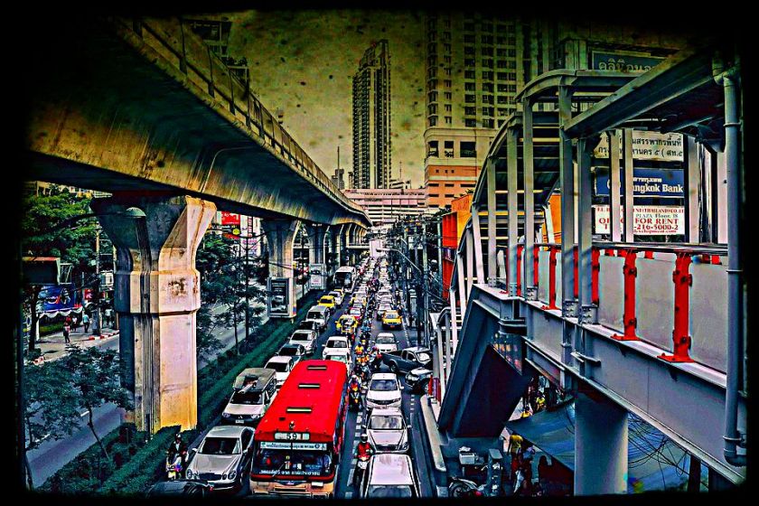 Bangkok traffic jam with cars and trucks and motorcycles all backed up below tram lines