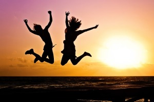 man and woman jumping for joy on a beach