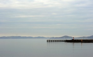 pier and lighthouse in distance across a lake